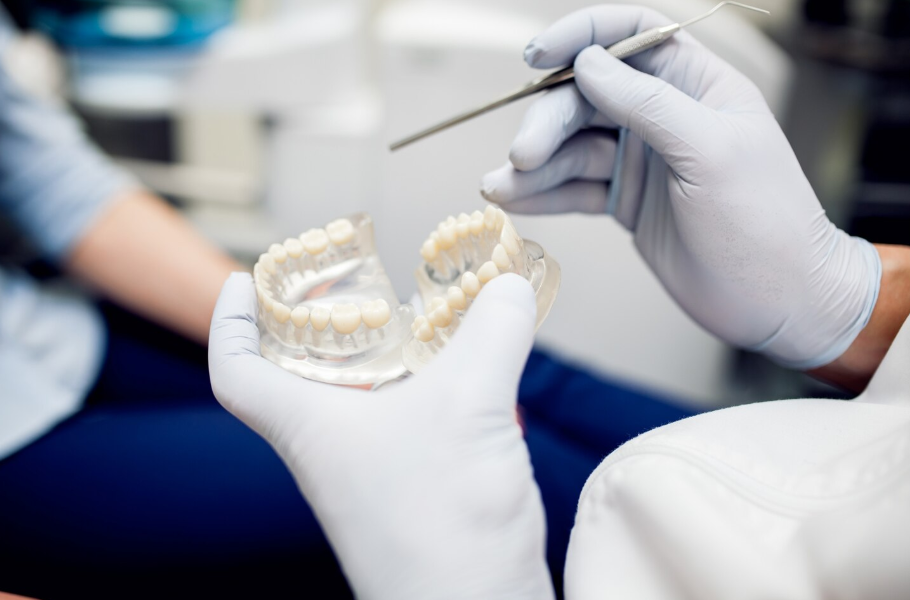 Лазерная имплантация зубов — стоматолог демонстрирует установку дентальных имплантов на модели челюсти