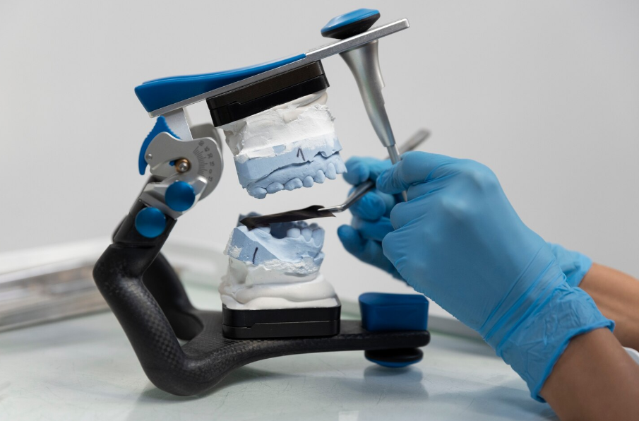 Изготовление зубного протеза по слепку челюсти для одноэтапной имплантации зубов — стоматолог-ортопед работает с моделью челюсти для установки имплантата.